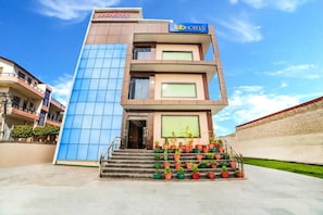 A multi-story building with a modern design, featuring a prominent facade with a mix of glass and concrete elements. - FabHotel Glorify Stay (Mathura)