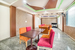 A conference room with a long table and chairs, a ceiling with green lighting accents, and a view of a building outside. - FabHotel Glorify Stay (Mathura)