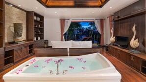 Ein geräumiges Badezimmer mit einer großen Badewanne, Holzschränken und Blick ins Freie.