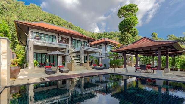 Ein modernes Resort mit Pool, Sitzgelegenheiten im Freien und Blick auf üppiges Grün.