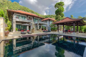 Een modern resort met een zwembad, terras en uitzicht op weelderige begroeiing.