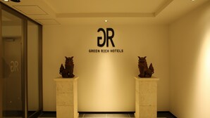 A lobby with a reception desk, two decorative animal statues, and a wall sign for Green Rich Hotels. - Green Rich Hotel & Capsule Naha Artificial Hot Spring Futamata Yunohana (Naha)