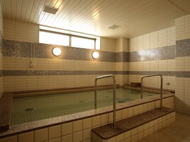 Una piscina con paredes de azulejos y un ventanal encima.
