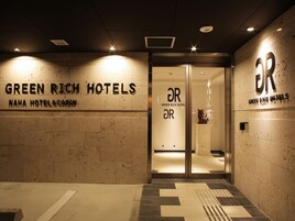 The exterior of Green Rich Hotels with a modern design, including a glass door entrance and signage.