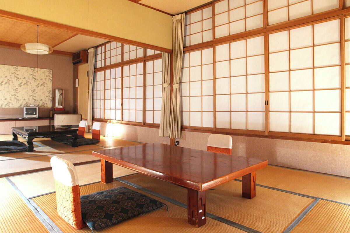 Ein traditioneller japanischer Raum mit Tatami-Mattenfußboden, einem niedrigen Holztisch und Shoji-Schirmwänden.