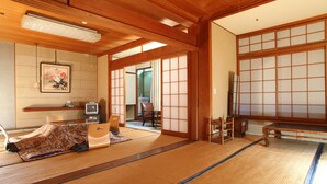 A traditional Japanese room with tatami flooring, a tatami mat-covered bed, a television, and sliding doors. - Hatsunoyu hotel (Yamanouchi)