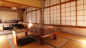 A traditional Japanese room with tatami flooring, a low wooden table, and sliding shoji doors. - Hatsunoyu hotel (Yamanouchi)