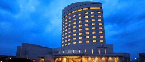 A hotel with a modern design, featuring a curved facade and multiple illuminated windows.