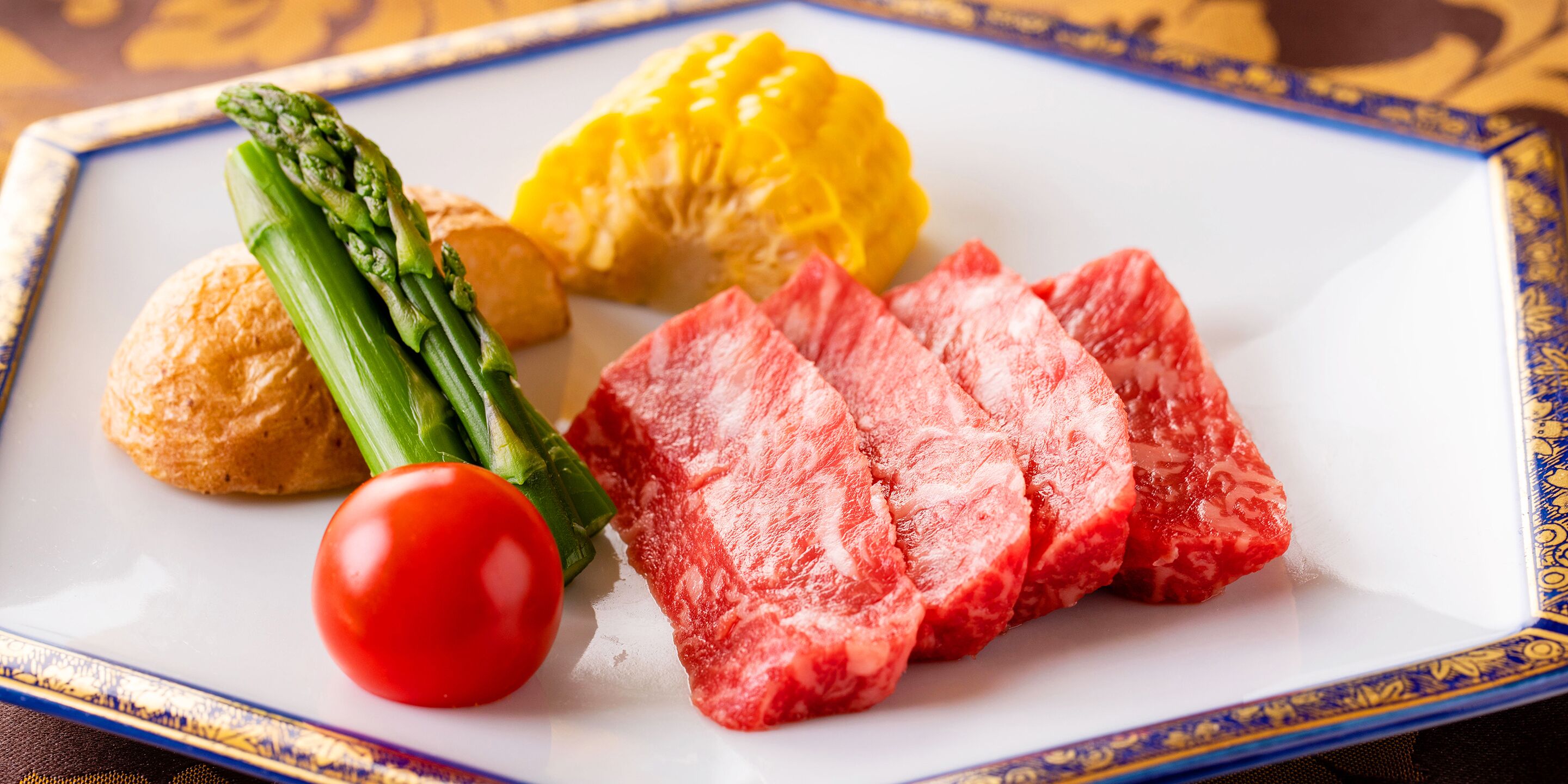 Un plato con filete, espárragos, tomate y pimiento amarillo.