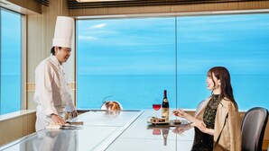 Een kok bereidt eten aan een tafel met uitzicht op zee.
