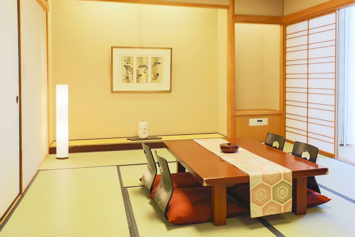 Ein traditioneller japanischer Raum mit Tatami-Bodenbelag, einem niedrigen Tisch und Shoji-Schirmwänden.