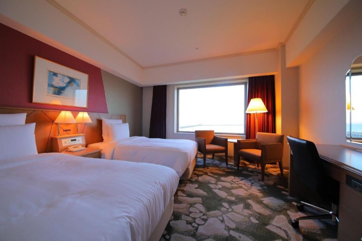 Een hotelkamer met twee bedden, een bureau, een stoel en een televisie.