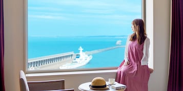 Habitación con un amplio ventanal que da a un muelle y un barco.