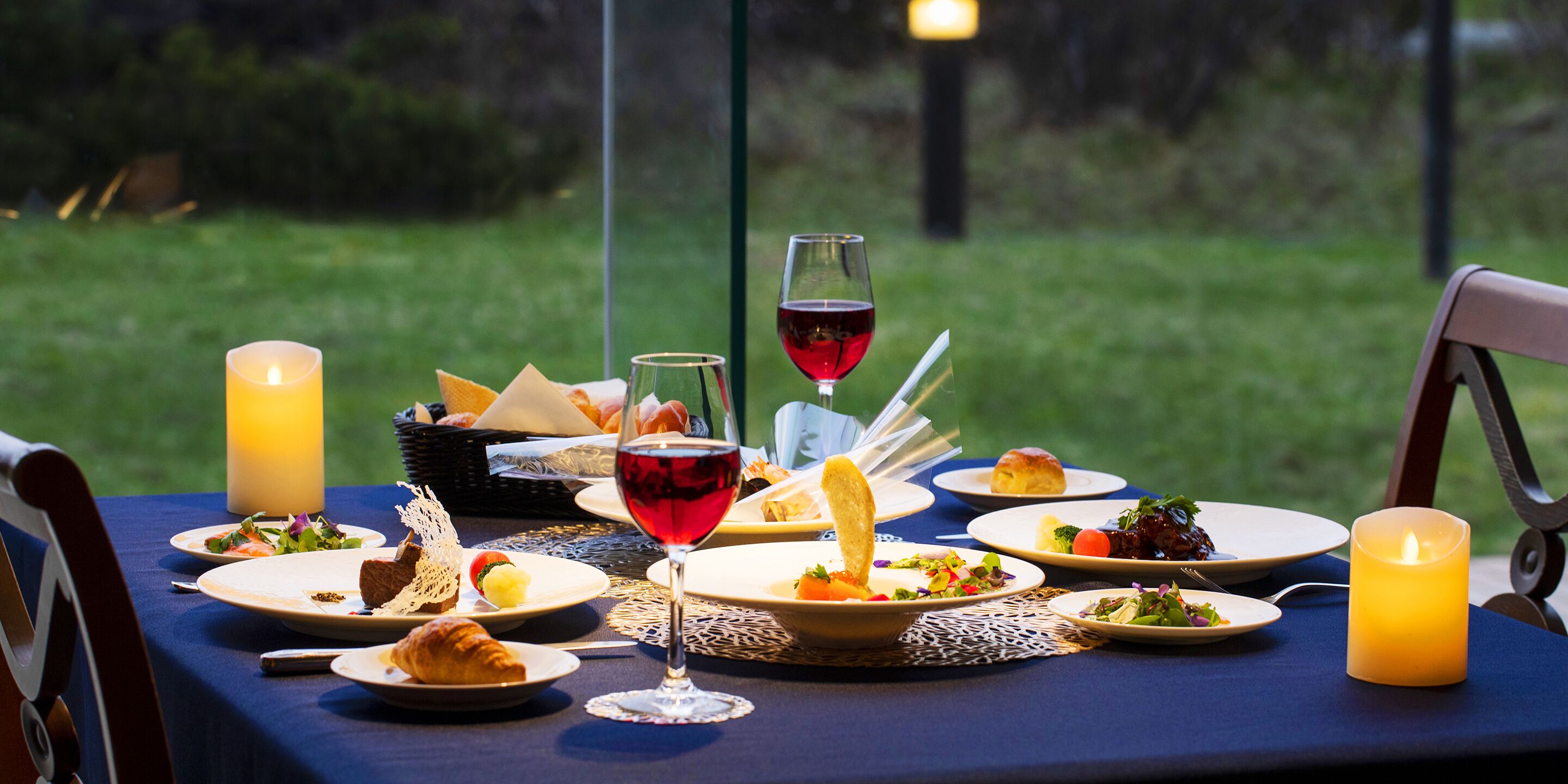 A table set for a meal with various dishes, glasses of wine, and candles.