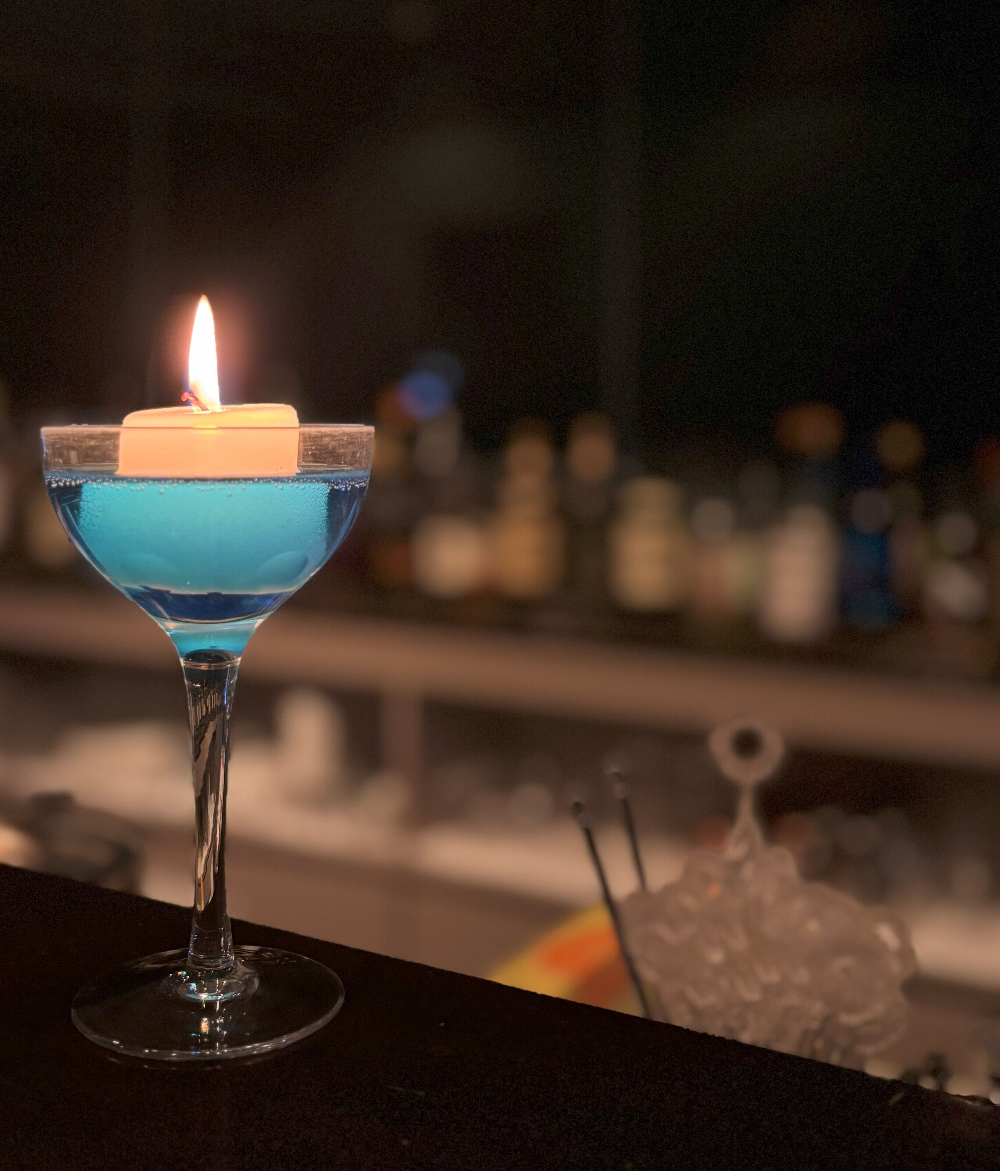 Una copa de cóctel con una vela encendida sobre una barra.