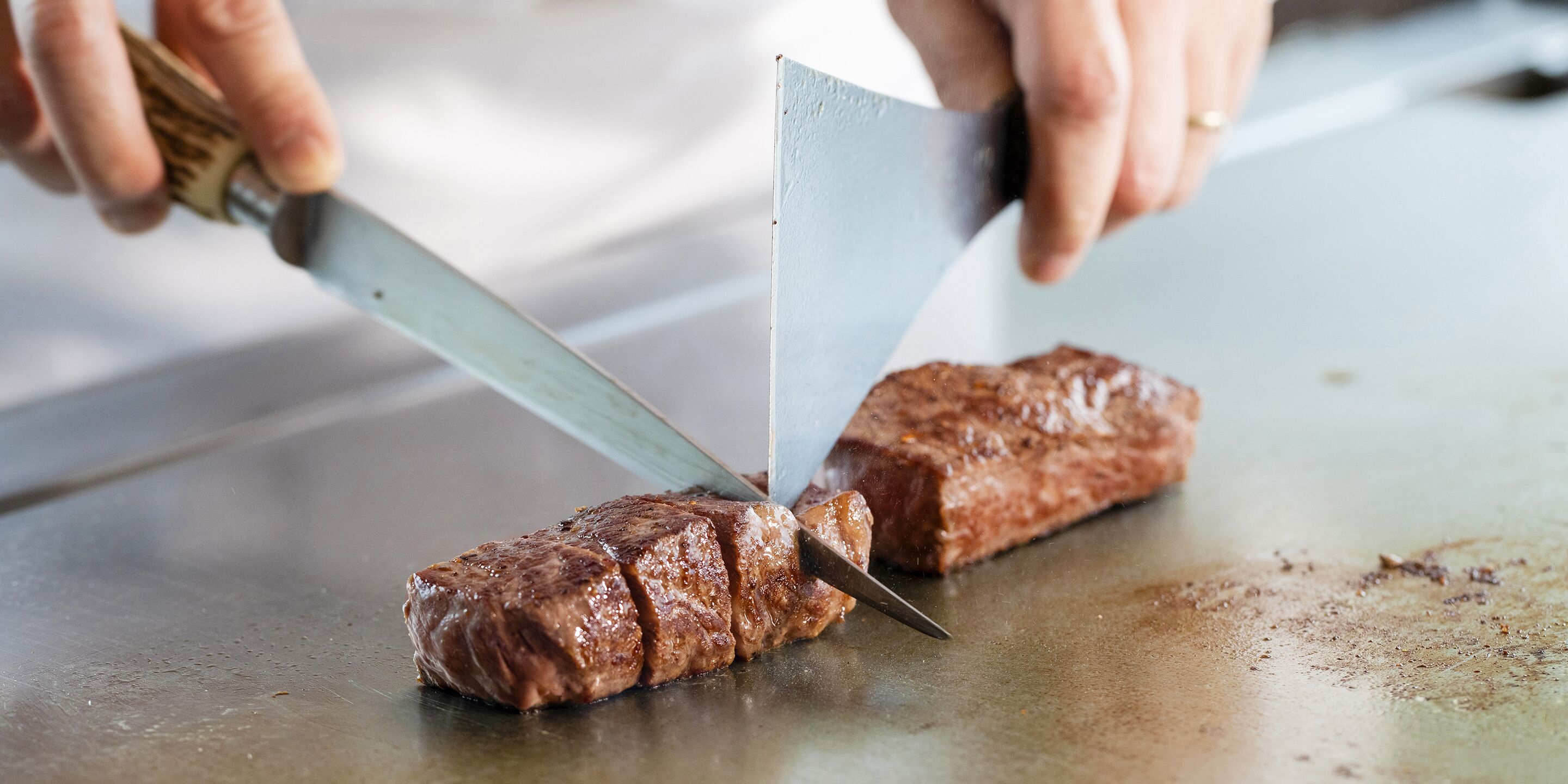 Una persona che affetta una bistecca su un tagliere.