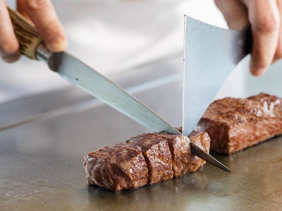 Una persona che affetta una bistecca su un tagliere.