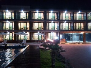 Ein Hotel mit mehreren Etagen, Außenbereich mit Sonnenschirmen und einem Poolbereich.