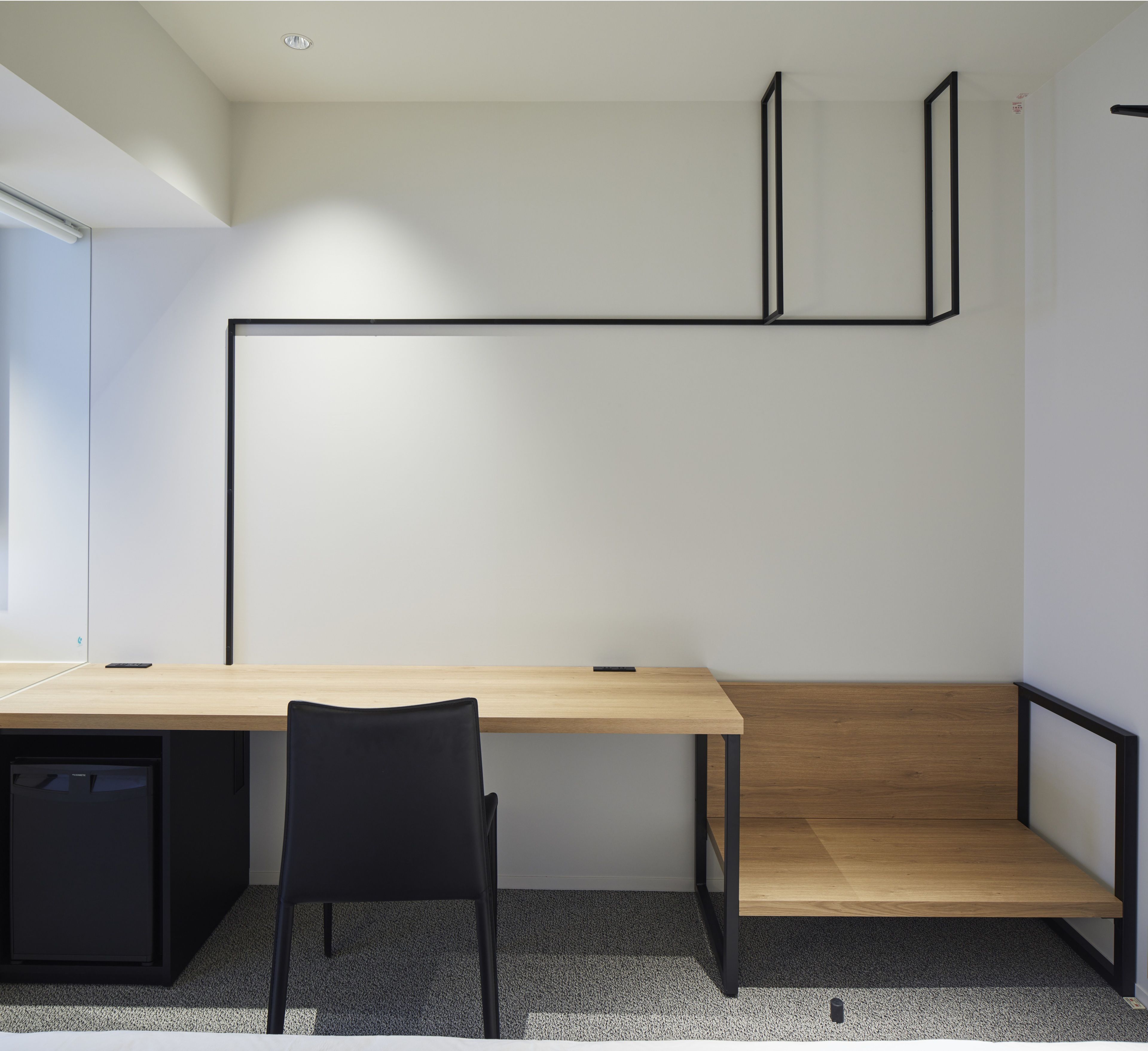 A modern office space with a wooden desk, black office chair, and a built-in bench.
