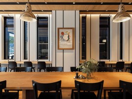 Un comedor moderno con una mesa de madera, sillas negras e iluminación colgante.