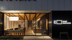 Ein moderner Hotel Eingangsbereich mit einer Rezeption, einer Sitzecke und einem sichtbaren Schild für das Hotel und die Zimmer.