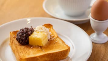 A breakfast plate with toast, butter, and jam, a cup of coffee, and a boiled egg on a table.