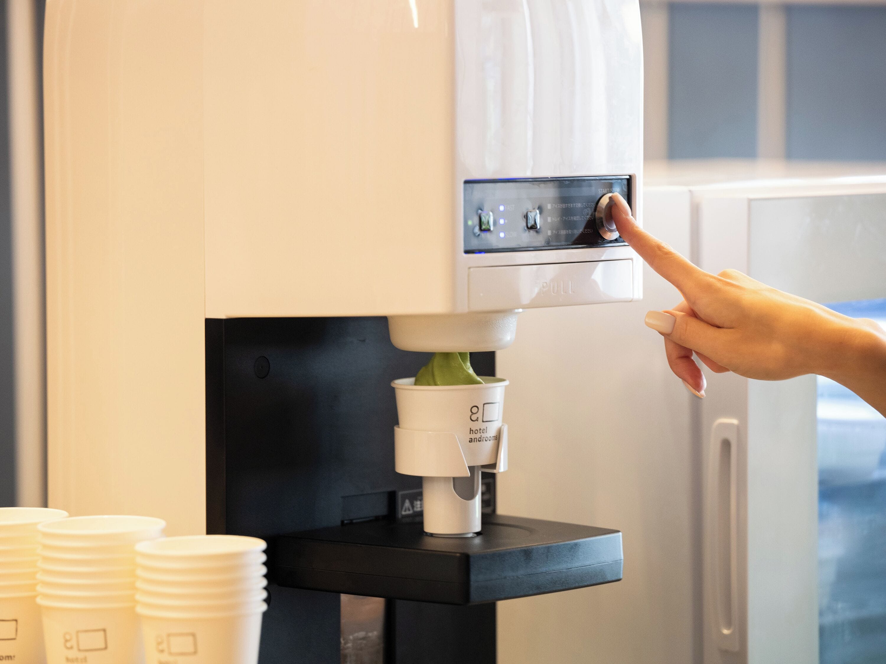 A coffee machine with a button panel and a cup dispenser.
