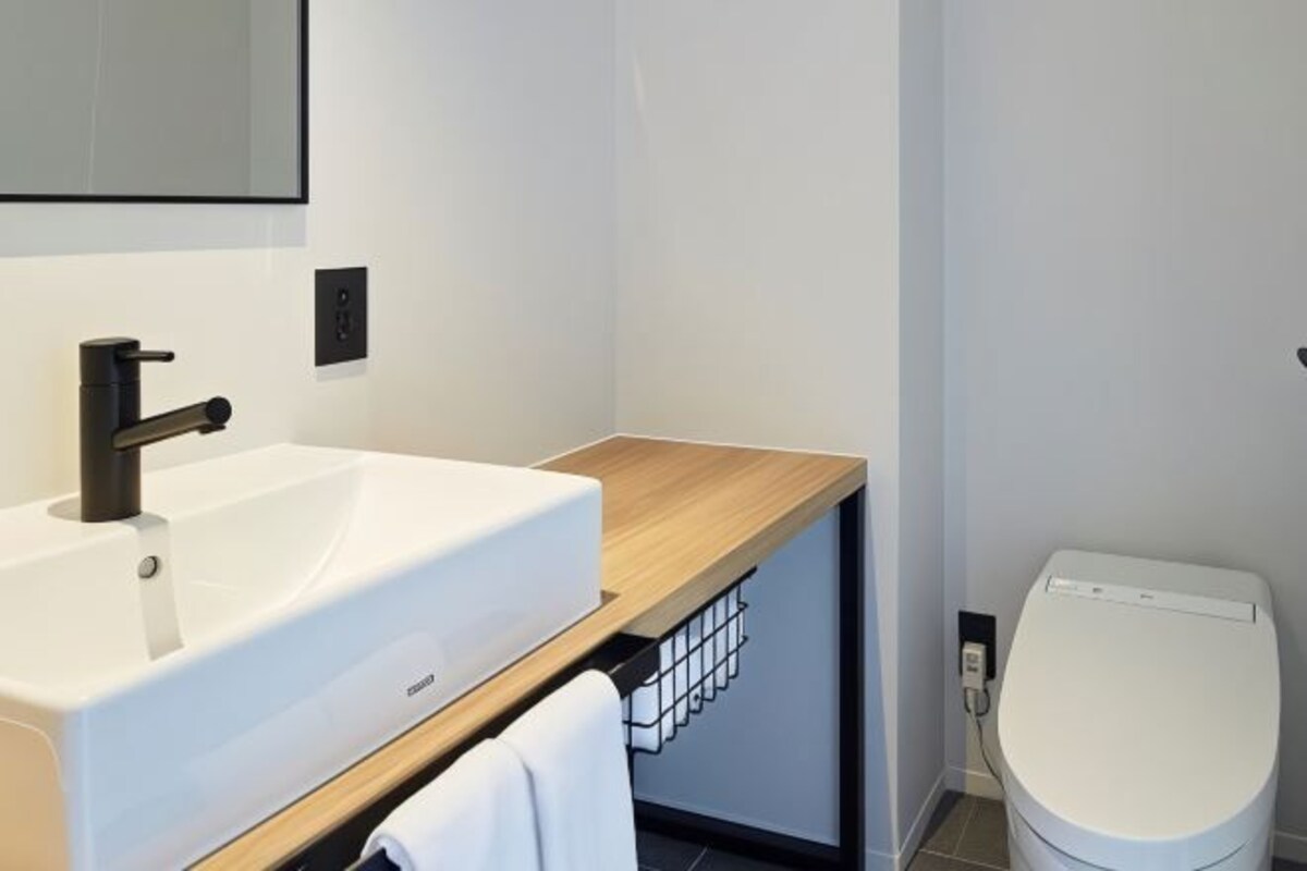 Une salle de bain moderne avec un lavabo blanc, un plan de toilette en bois et des toilettes blanches.