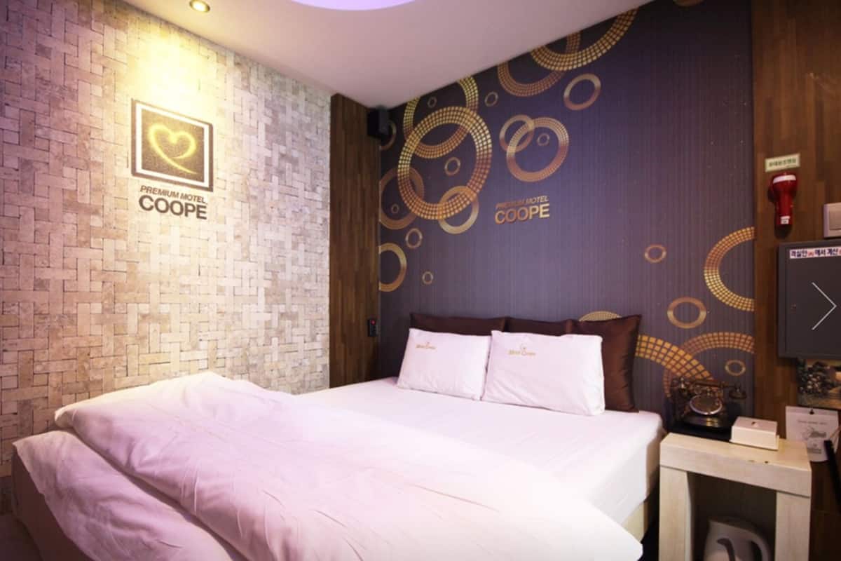 A hotel room with a brick-patterned wall, a bed with white linens, and a decorative wall with circular patterns.