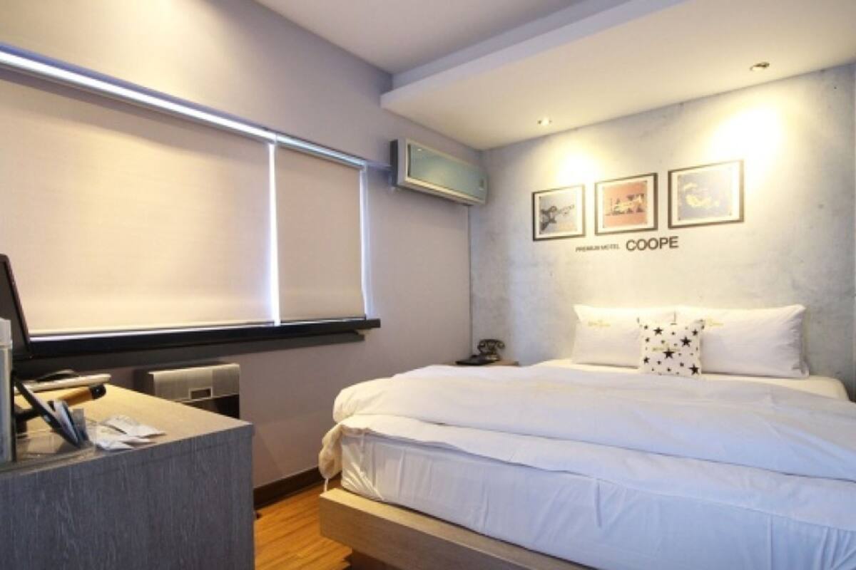 A hotel room with a bed, a desk, and a TV mounted on the wall.