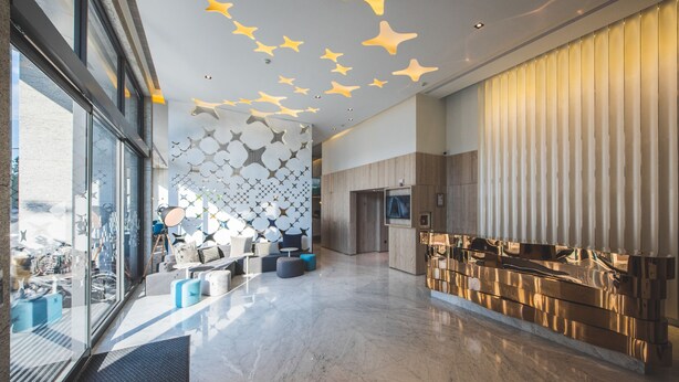 A modern lobby with a glass wall, a patterned wall, and a reflective wall. - Hotel Ramble (Taichung)
