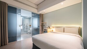 A modern hotel room with a large bed, a glass shower area, and a bedside table with a lamp. - Hotel Ramble (Taichung)