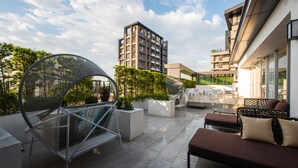 A rooftop terrace with modern outdoor furniture, a spherical seating area, and a view of a high-rise building. - Hotel Ramble (Taichung)