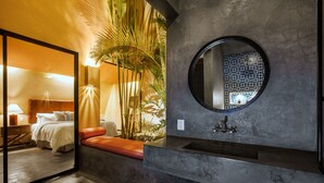Une salle de bain moderne avec un miroir rond, un lavabo et un banc.