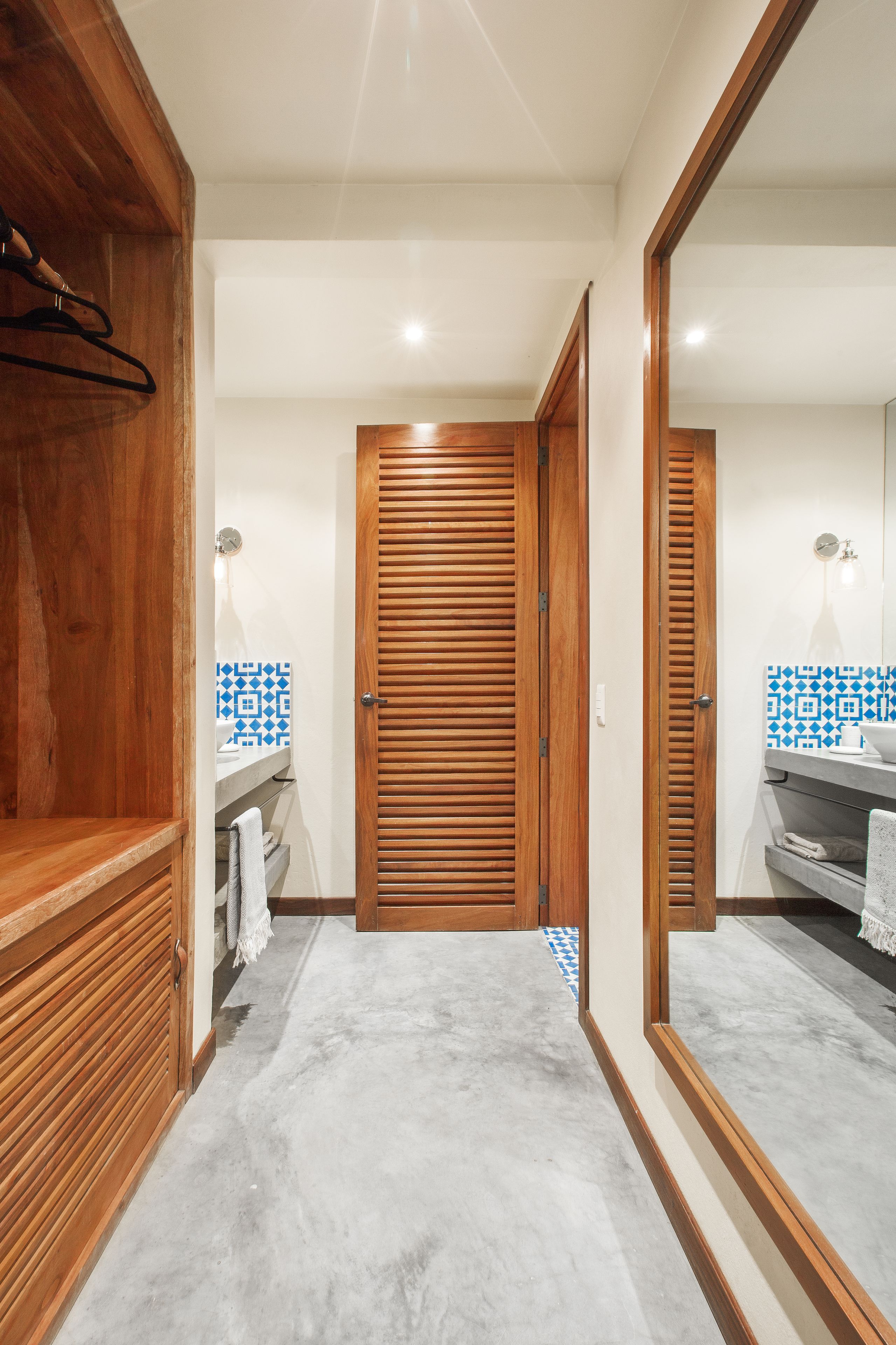 A bathroom with wooden cabinets, a tiled backsplash, and a large mirror.