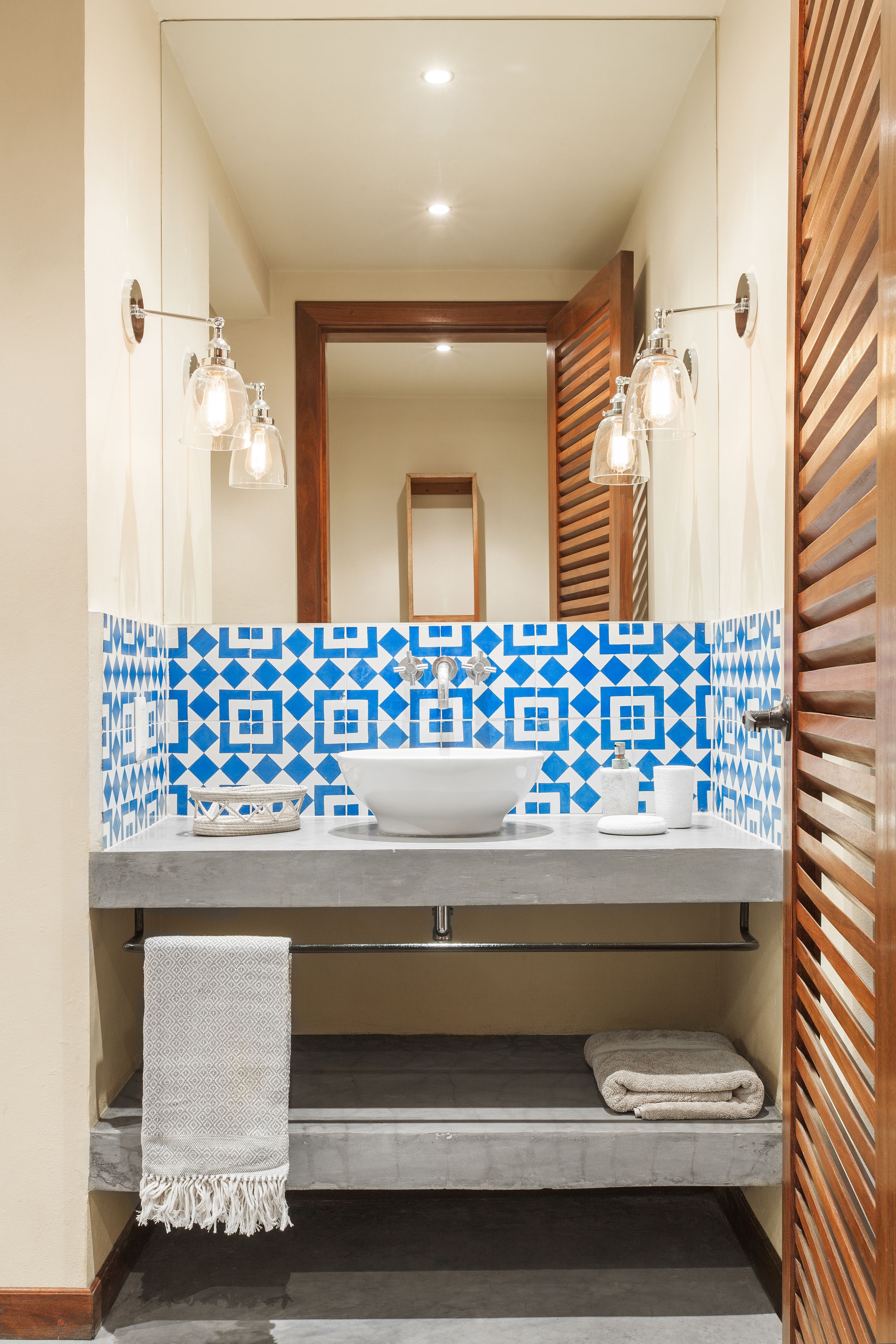 A bathroom with a white sink, blue patterned tiles, and a towel rack.