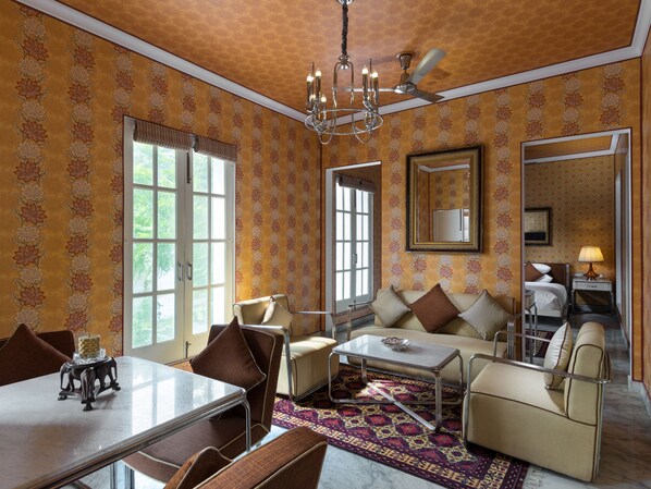 Une pièce comprenant une table à manger, des chaises, un canapé, un tapis à motifs et un ventilateur de plafond.