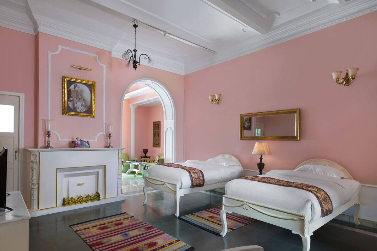 Una habitación de hotel con dos camas, un comedor y un baño.