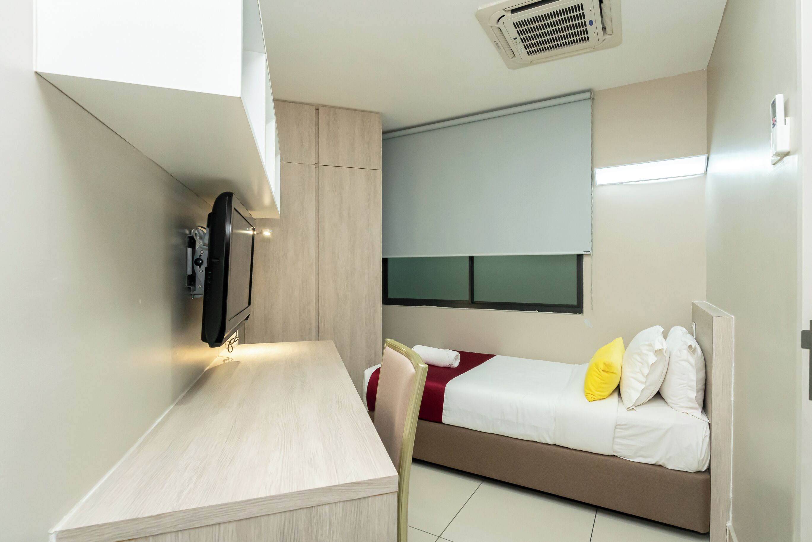 Una habitación compacta con cama, un escritorio pequeño y televisión.