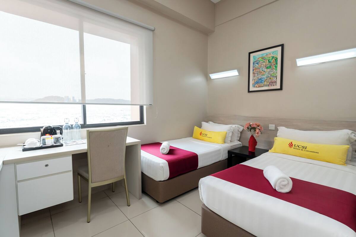 A hotel room with two beds, a desk, and a chair.