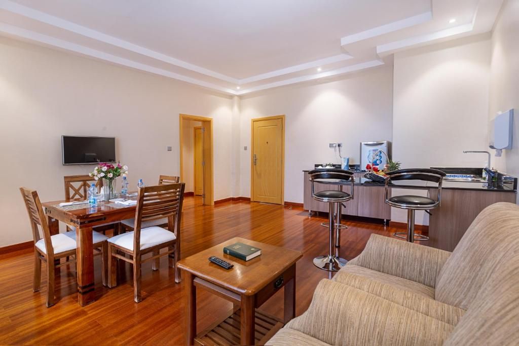 A modern living room with a dining area, a kitchen, and a TV mounted on the wall.
