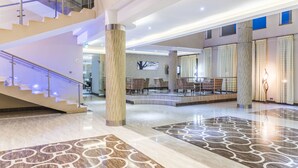 A spacious lobby with a marble floor, a staircase, and seating areas. - Three Steers Hotel (Meru)