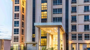 A multi-story hotel with a central entrance, large windows, and a covered walkway. - Three Steers Hotel (Meru)