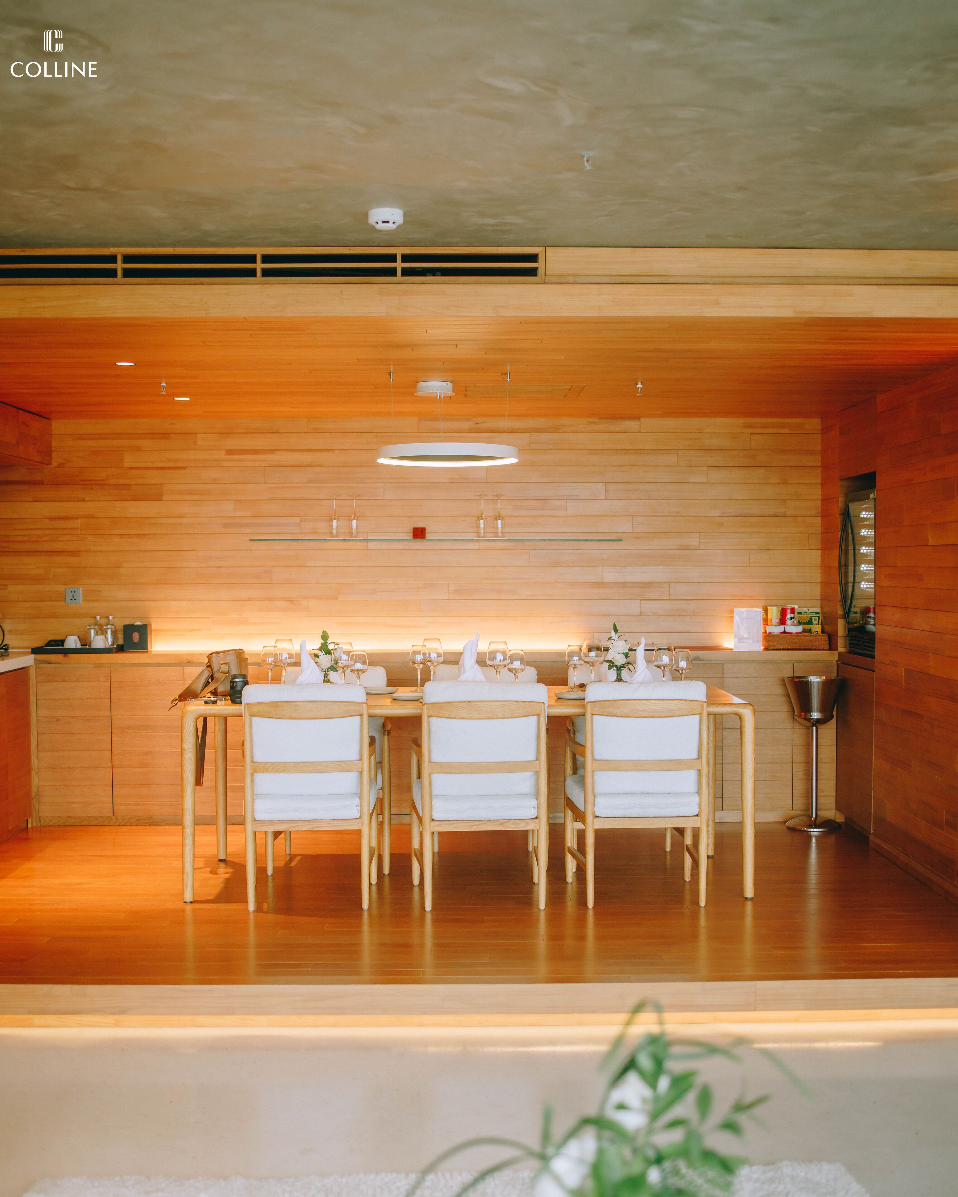 Een moderne keuken met houten kastjes, een centraal eiland en een eethoek met witte stoelen en een glazen tafel.