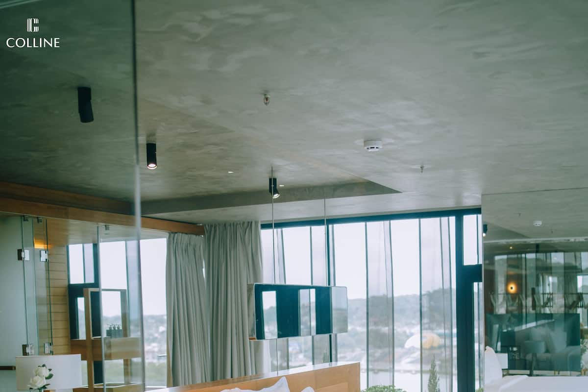 A modern bedroom with a large bed, bedside tables, a mirror, and a view of the city through large windows.
