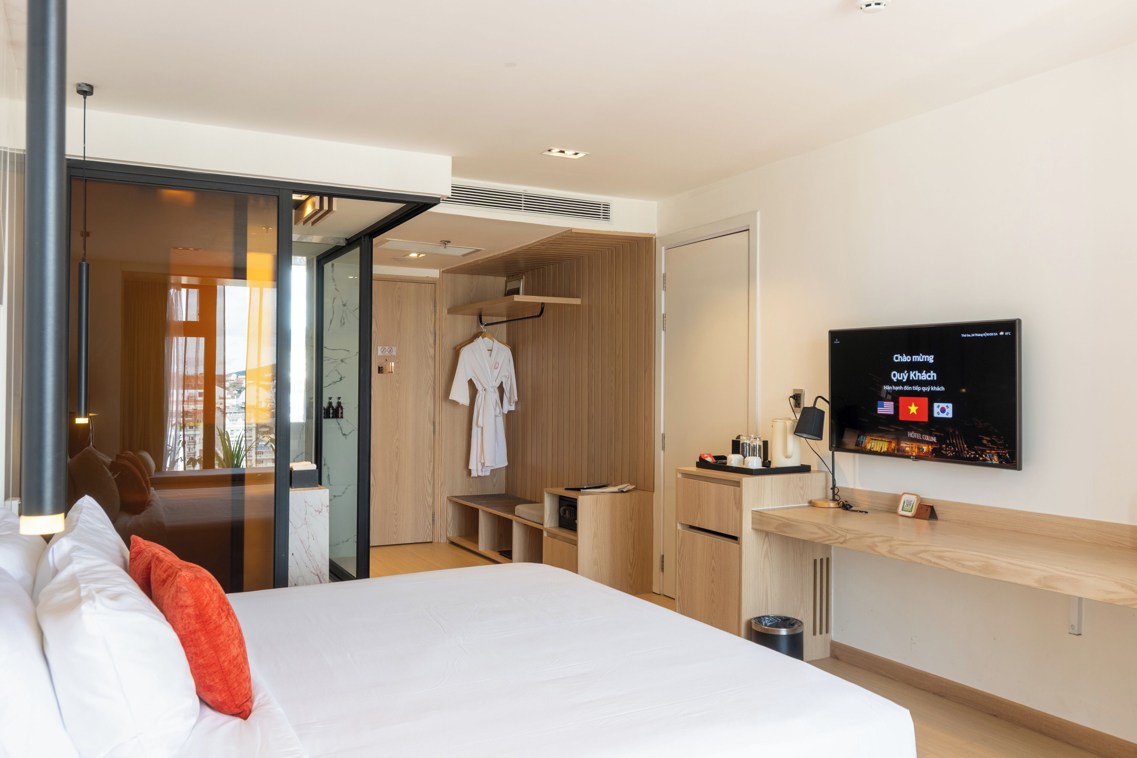 A modern hotel room with a bed, a TV, a desk, and a walk-in closet.