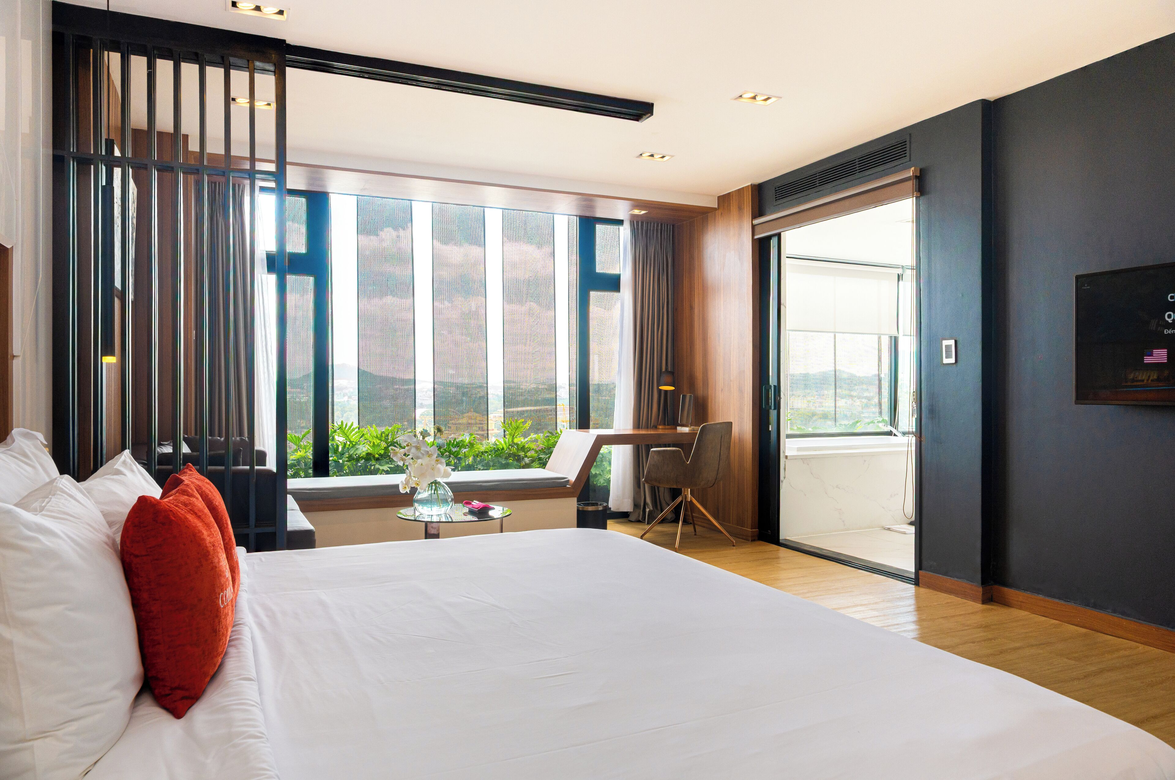Una habitación de hotel moderna con una cama grande, un escritorio y vistas al exterior.