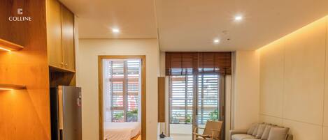 Habitación de hotel compacta con kitchenette, cama, zona de estar y vistas al exterior.
