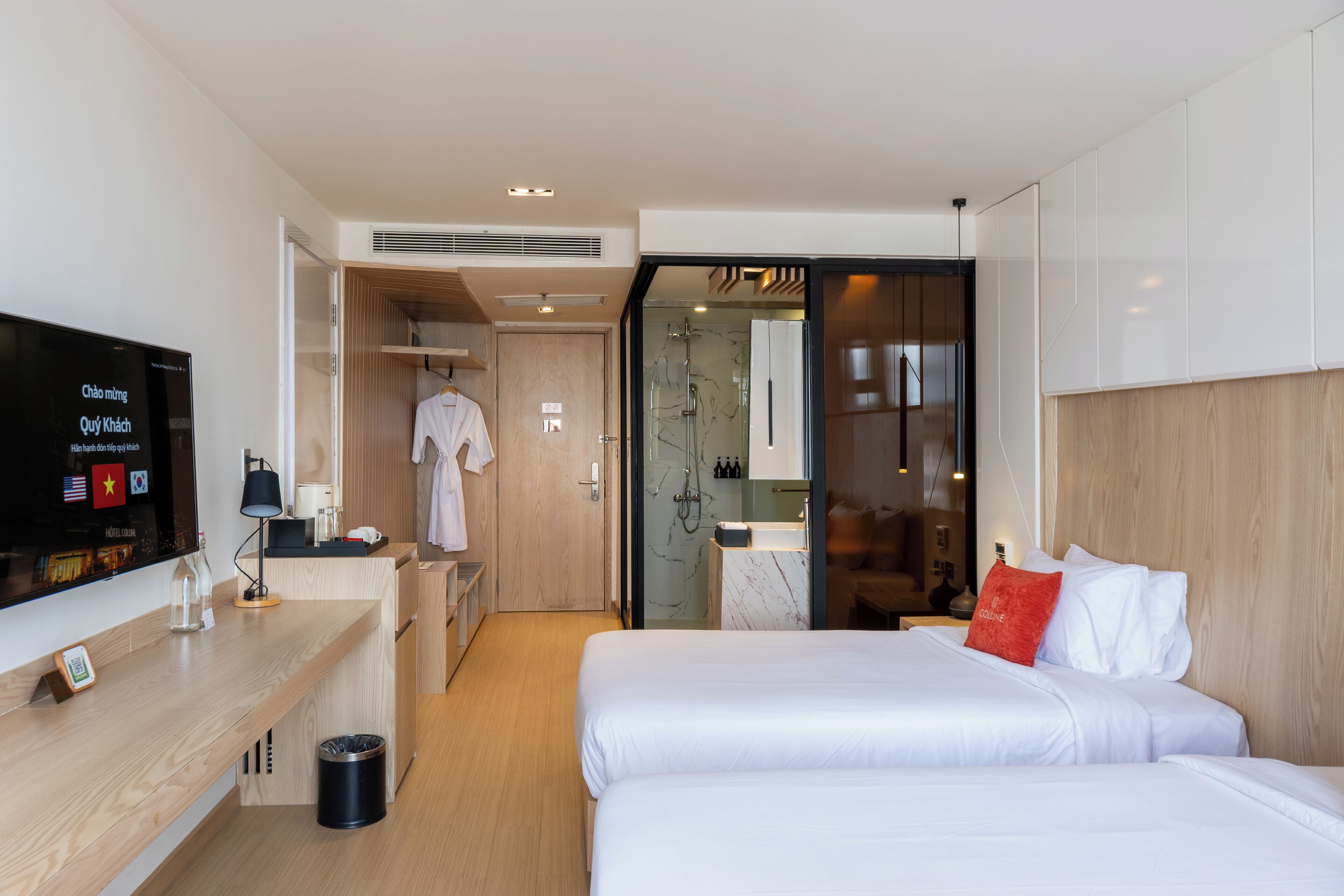 Habitación de hotel con cama, televisor, escritorio y baño visible a través de una puerta abierta.