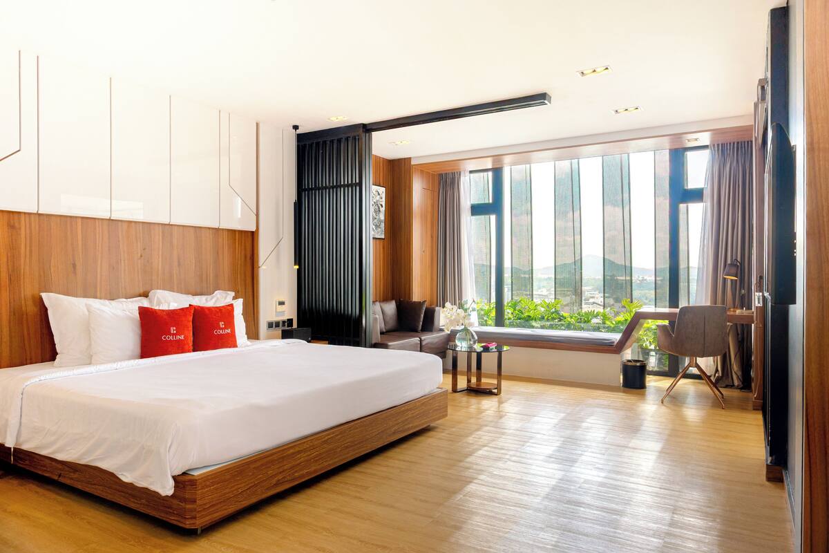 A modern hotel room with a large bed, a desk, and a view of the city.